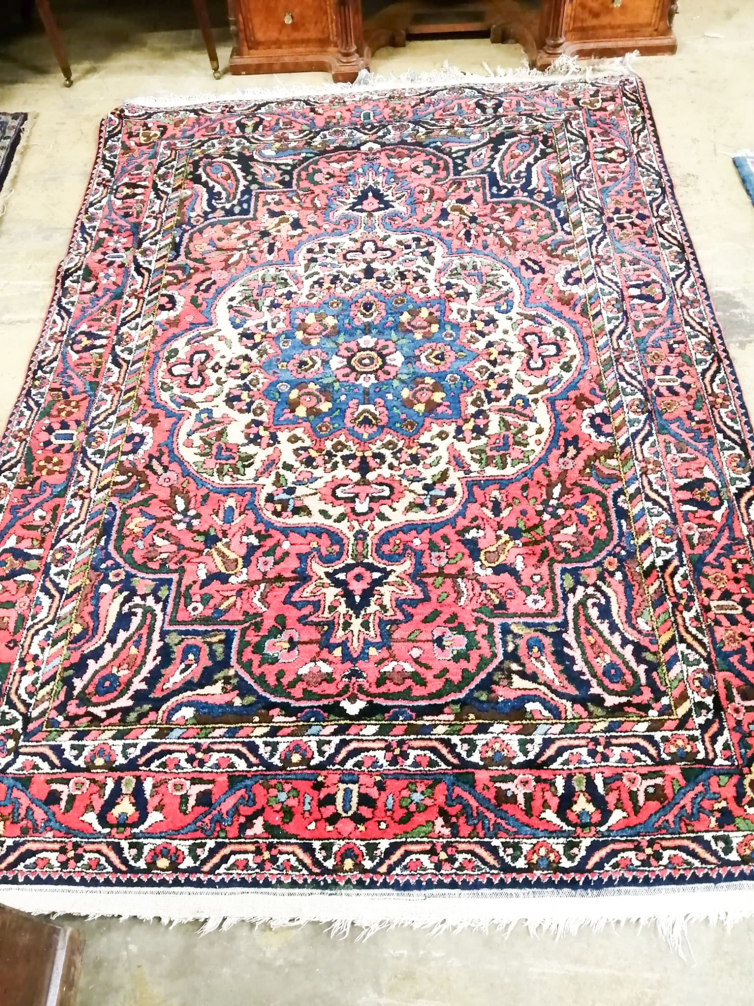An Eastern red ground carpet with multi-coloured floral decoration and a Caucasian red ground geometric patterned rug, larger 220 x 155cm
